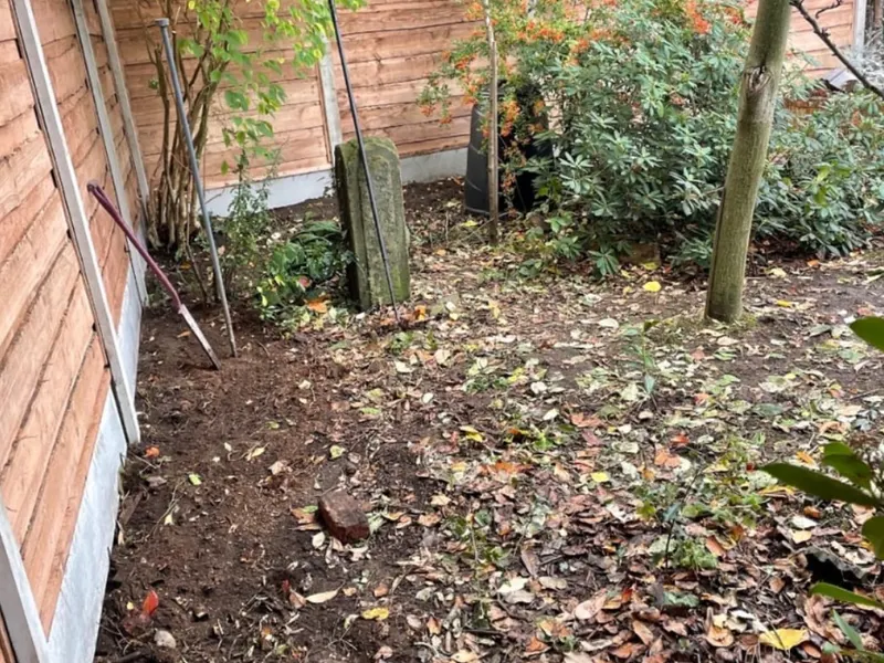 Before: overgrown corner turned into a sandstone patio with new fencing
