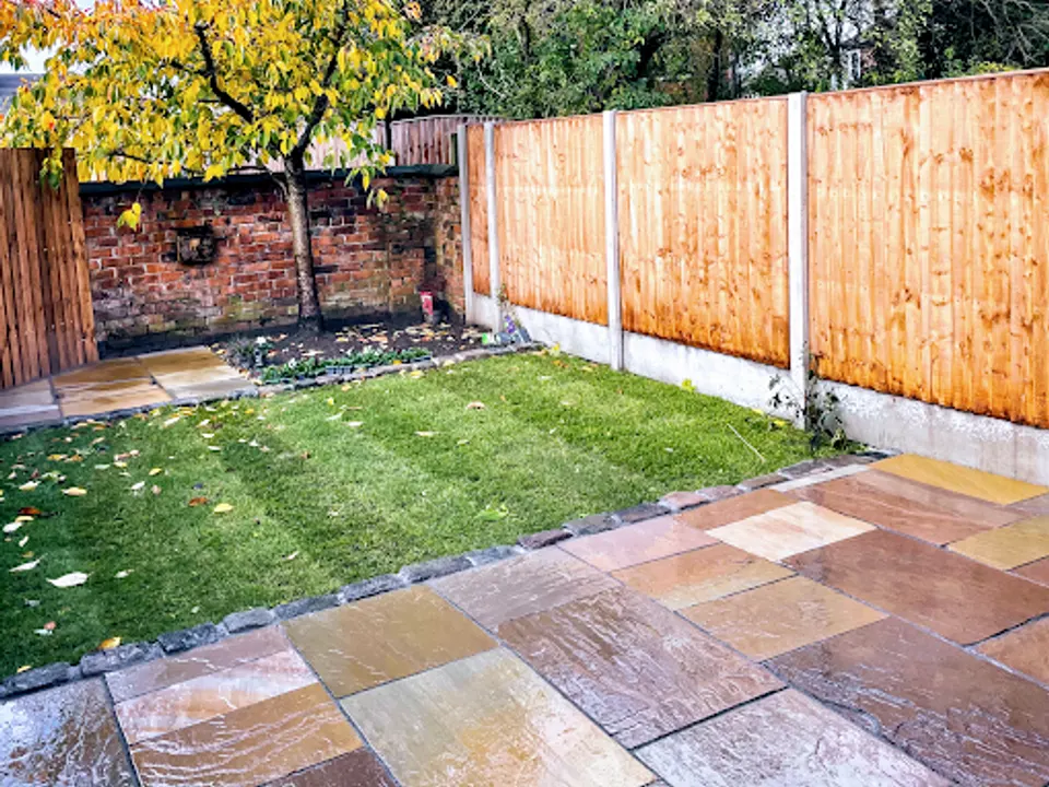 New close-board fence with concrete posts behind a fresh turf lawn