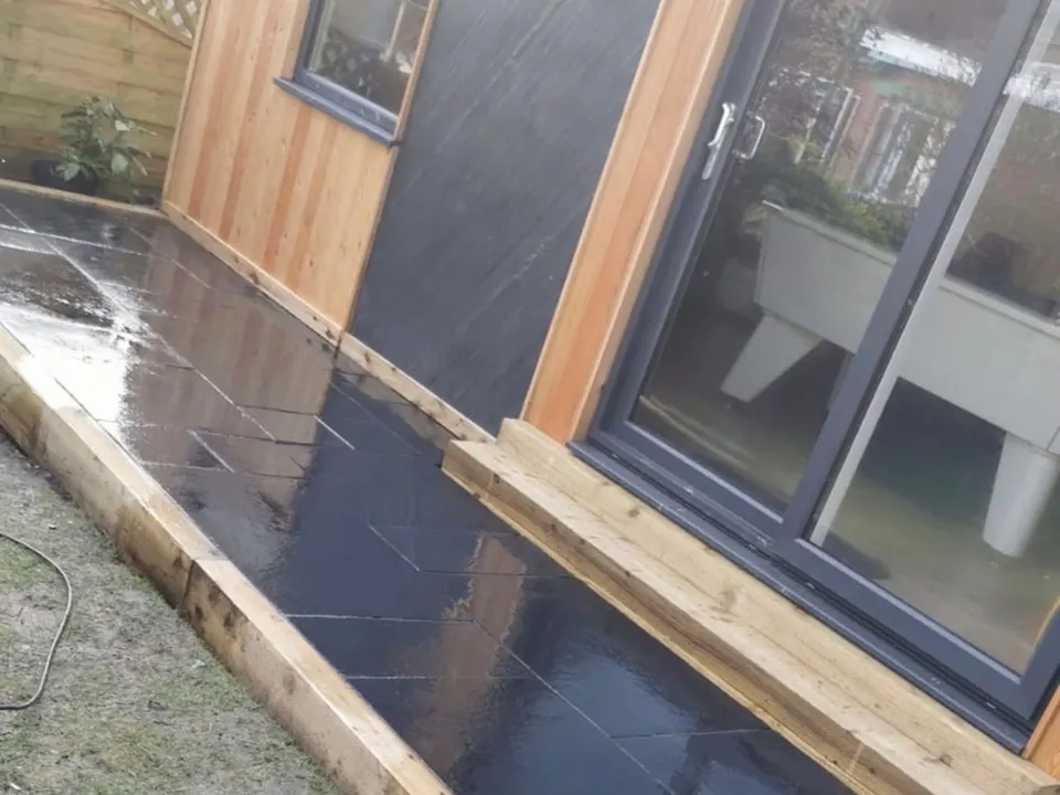 Slate paving and sleeper edging beside a garden room
